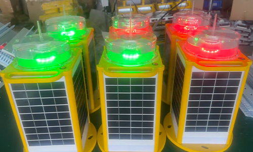 IALA Marine Lantern 2 YFFY Lights Row of yellow solar powered lanterns with solar panels each topped by green or red LED indicators on a workshop table