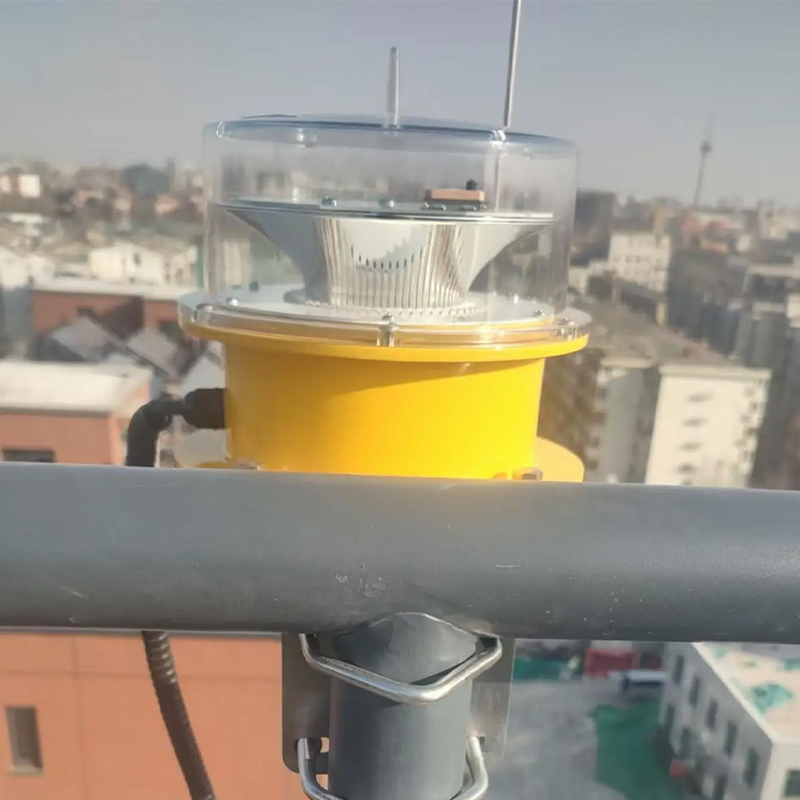 Yellow rooftop beacon light with a clear plastic dome mounted on a railing overlooking an urban cityscape