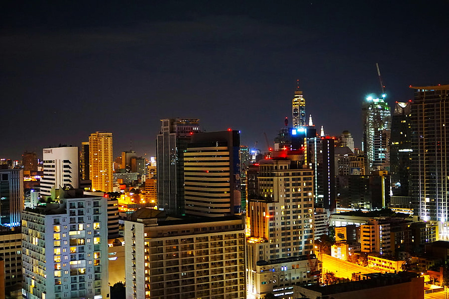 Nighttime city skyline with illuminated skyscrapers and streets stretching across the horizon.