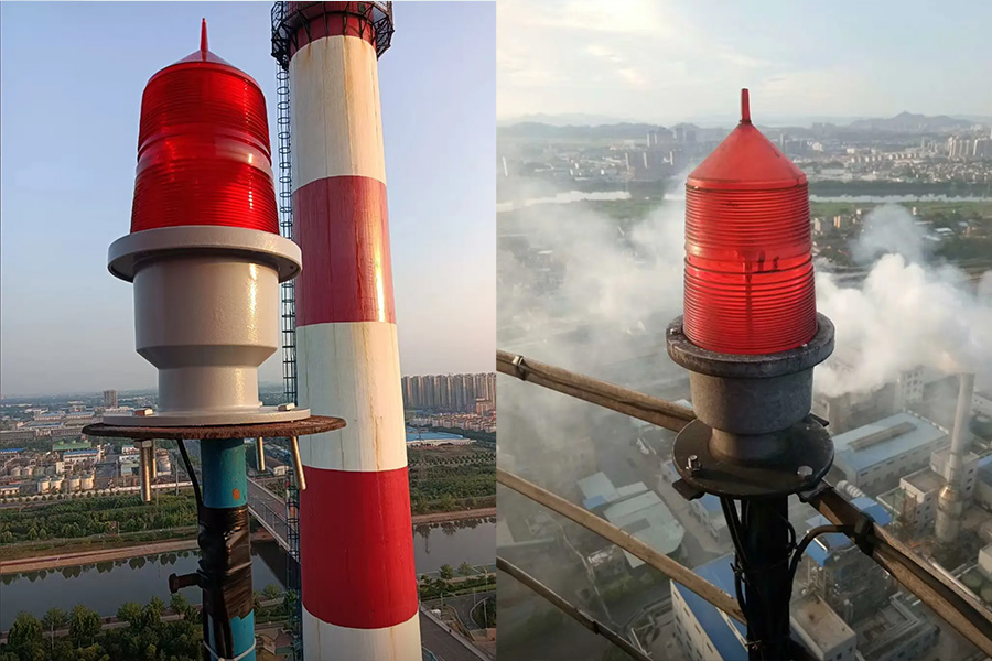 Two red beacon lights atop a tall striped tower overlooking a city and river On the left a larger red light with a white base on the right a smaller red light amid hazy skyline